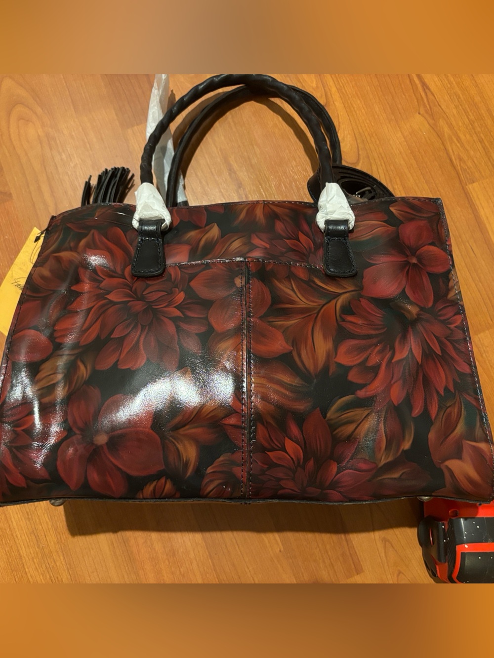 Red Floral Patricia Nash Tote with Black Handles and Tassel Accent.